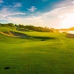 An ocean side golf course during sunset.