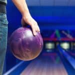 A man holding a bowling ball looking down the alley.