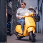 A man riding on a yellow scooter.