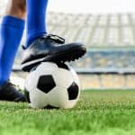 An athlete wearing a pair of black soccer cleats on a football field.