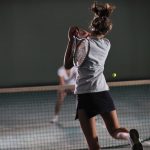 Two female tennis players midgame, with one player about to miss the shot and lose a point due to an unforced error.
