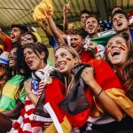 A group of soccer fans supporting different countries having fun while watching a match.